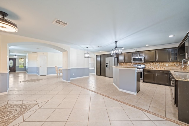 20151 Pioneer Ridge Dr, Cypress, TX 77433 - kitchen with appliances with stainless steel finishes, arched walkways, dark brown cabinetry, a sink, and recessed lighting