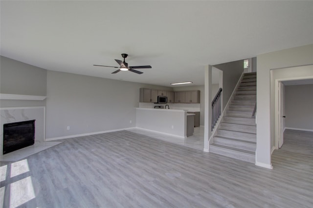 11623 Silent Elm St, Houston, TX 77044 - unfurnished living room with a premium fireplace, stairway, baseboards, a ceiling fan, and light wood-style floors