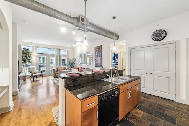 kitchen featuring a sink, black dishwasher, brown cabinetry, a kitchen island with sink, and open floor plan