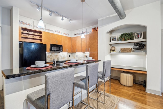 kitchen featuring black appliances, tasteful backsplash, light wood-style flooring, pendant lighting, and brown cabinets