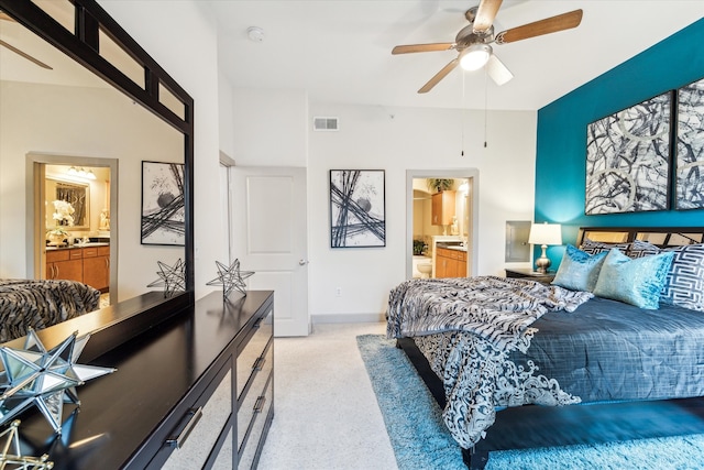 bedroom with connected bathroom, a ceiling fan, and light colored carpet