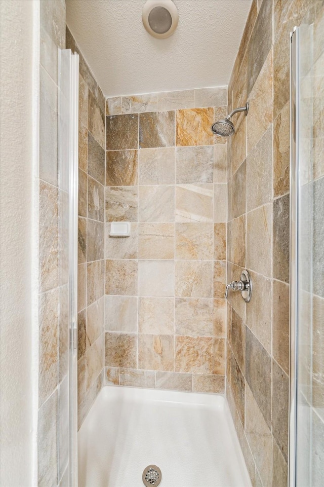 full bath with a shower stall and a textured ceiling