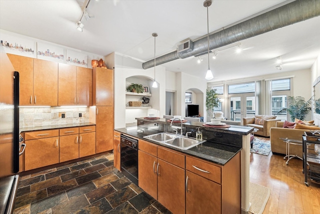 kitchen featuring a sink, rail lighting, black dishwasher, open floor plan, and arched walkways