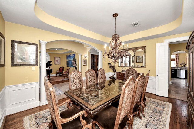 5701 Sugar Hill Dr, Houston, TX 77057 - dining room with arched walkways, decorative columns, a wainscoted wall, dark wood-type flooring, and a raised ceiling