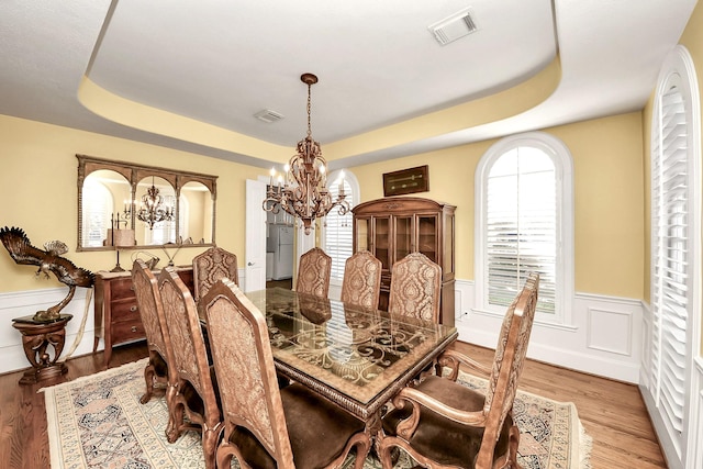 5701 Sugar Hill Dr, Houston, TX 77057 - dining area featuring a chandelier, a tray ceiling, wainscoting, and wood finished floors