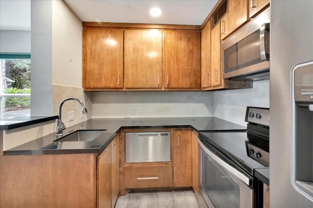 411 Westmoreland St Unit 1, Houston, TX 77006 - kitchen featuring appliances with stainless steel finishes, a sink, brown cabinetry, backsplash, and recessed lighting