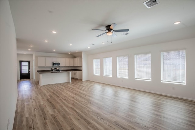 22065 Juniper Crossing Dr, New Caney, TX 77357 - unfurnished living room with light wood finished floors, a ceiling fan, recessed lighting, and baseboards