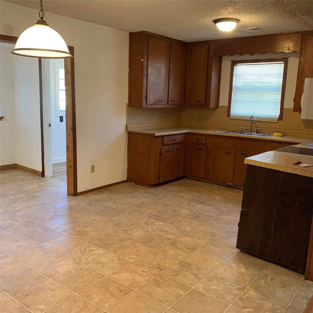 324 Persimmon Rd, Onalaska, TX 77360 - kitchen featuring a sink, light countertops, hanging light fixtures, and baseboards
