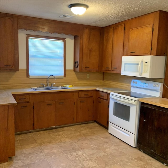 324 Persimmon Rd, Onalaska, TX 77360 - kitchen with white appliances, a sink, light countertops, brown cabinets, and a textured ceiling