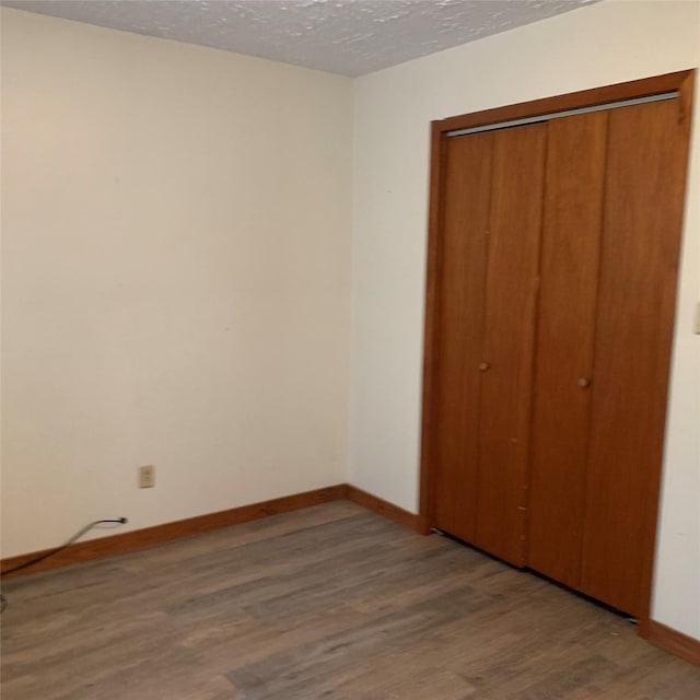 324 Persimmon Rd, Onalaska, TX 77360 - unfurnished bedroom featuring wood finished floors, a textured ceiling, baseboards, and a closet