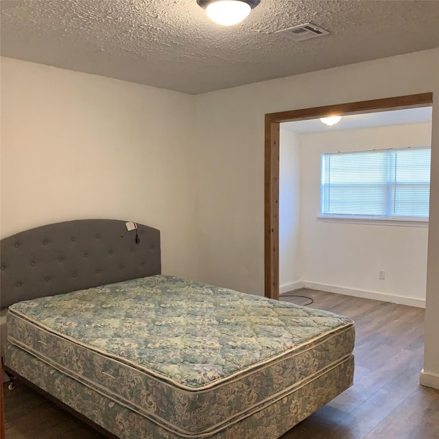 324 Persimmon Rd, Onalaska, TX 77360 - bedroom featuring wood finished floors, a textured ceiling, and baseboards