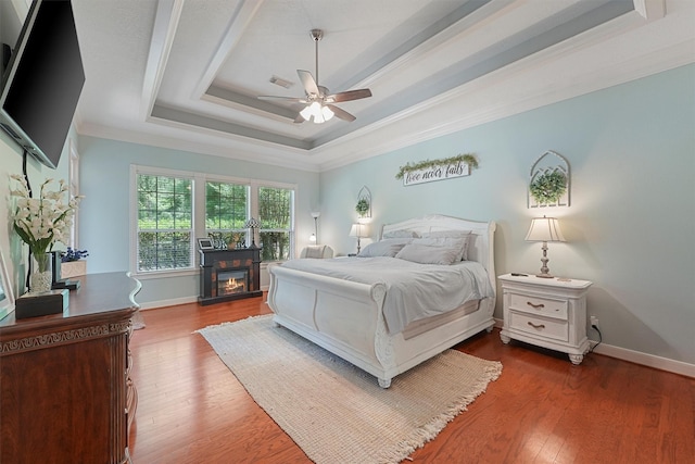 711 Valley Commons Dr, Huffman, TX 77336 - bedroom featuring a tray ceiling, ornamental molding, dark wood finished floors, baseboards, and ceiling fan