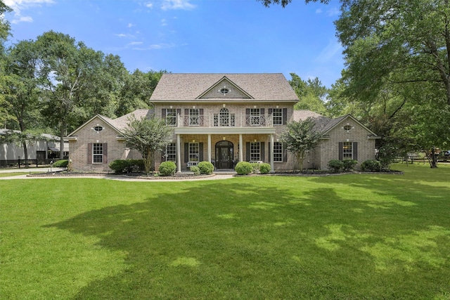 711 Valley Commons Dr, Huffman, TX 77336 - georgian-style home with brick siding, a front lawn, and a porch