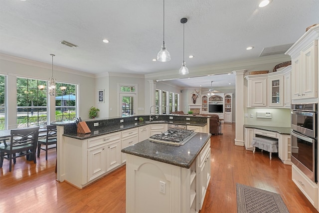 711 Valley Commons Dr, Huffman, TX 77336 - kitchen with a spacious island, appliances with stainless steel finishes, a sink, crown molding, and light wood-type flooring