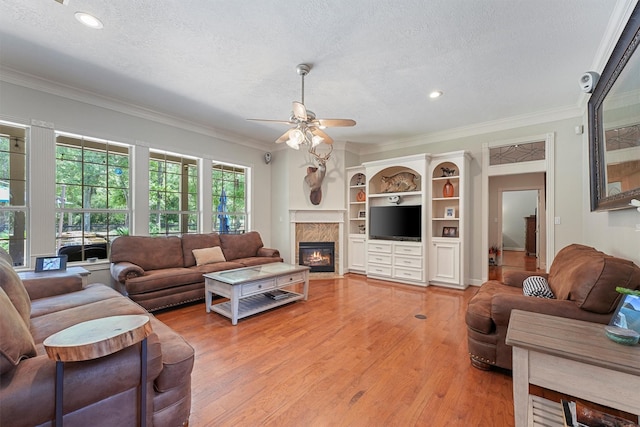 711 Valley Commons Dr, Huffman, TX 77336 - living room featuring a fireplace, crown molding, a ceiling fan, a textured ceiling, and light wood-style floors
