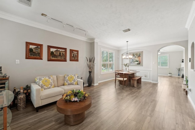 17150 Mountain Crest Dr, Spring, TX 77379 - living area with rail lighting, arched walkways, ornamental molding, healthy amount of natural light, and a chandelier