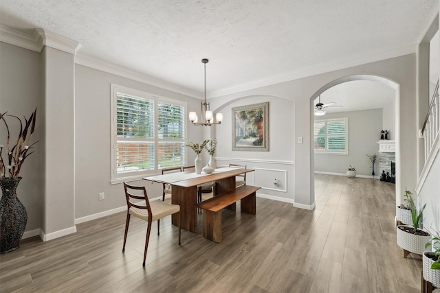17150 Mountain Crest Dr, Spring, TX 77379 - dining room with wood finished floors, arched walkways, a fireplace, ceiling fan, and ornamental molding