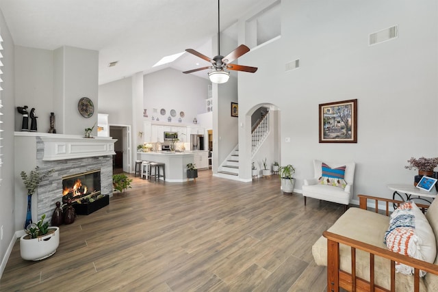 17150 Mountain Crest Dr, Spring, TX 77379 - living area featuring high vaulted ceiling, a ceiling fan, a stone fireplace, stairs, and wood finished floors