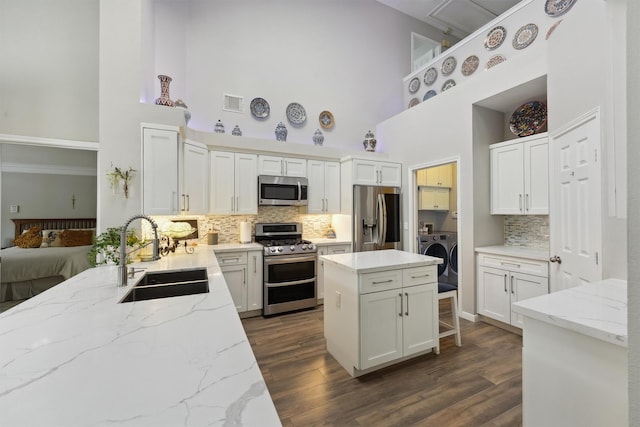17150 Mountain Crest Dr, Spring, TX 77379 - kitchen with appliances with stainless steel finishes, a sink, a high ceiling, washing machine and dryer, and tasteful backsplash