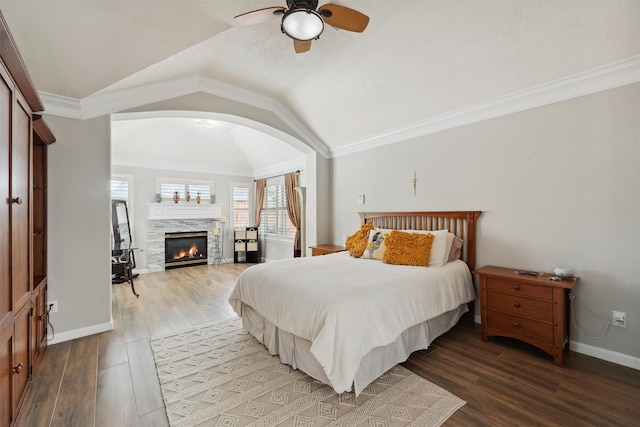 17150 Mountain Crest Dr, Spring, TX 77379 - bedroom featuring wood finished floors, vaulted ceiling, arched walkways, a glass covered fireplace, and baseboards