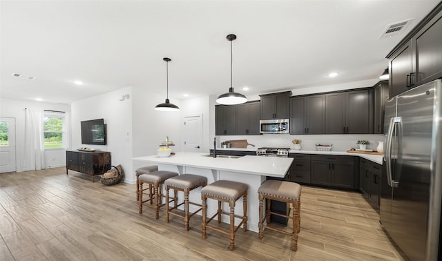 106 Kickapoo Dr, Anahuac, TX 77514 - kitchen featuring stainless steel appliances, a sink, decorative backsplash, a breakfast bar, and light wood-style floors