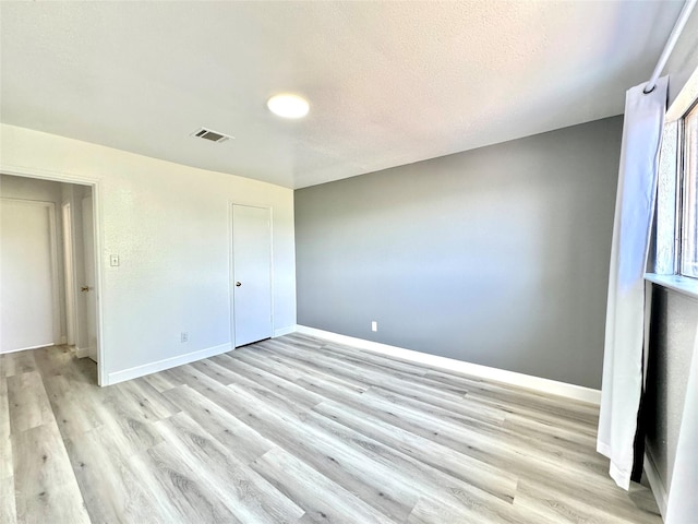 11127 Village Bend Ln Unit 1127, Houston, TX 77072 - unfurnished bedroom with light wood finished floors, baseboards, and a textured ceiling