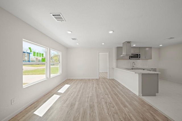 5763 Belneath St, Houston, TX 77033 - unfurnished living room with baseboards, recessed lighting, light wood finished floors, and a sink