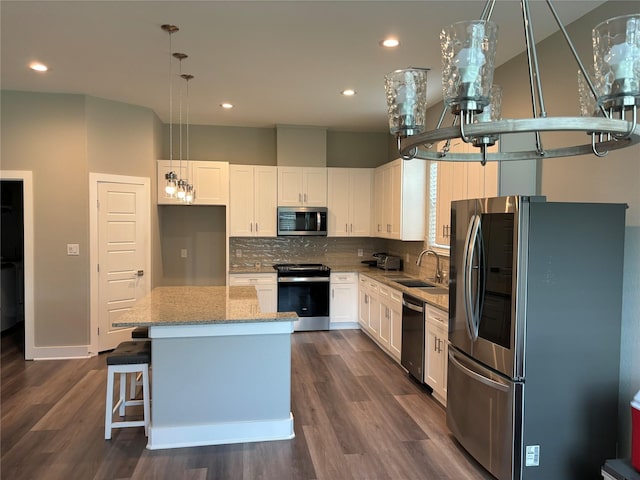 170 Nuuanu Ln, Bastrop, TX 78602 - kitchen with stainless steel appliances, a sink, white cabinets, light stone counters, and a kitchen island