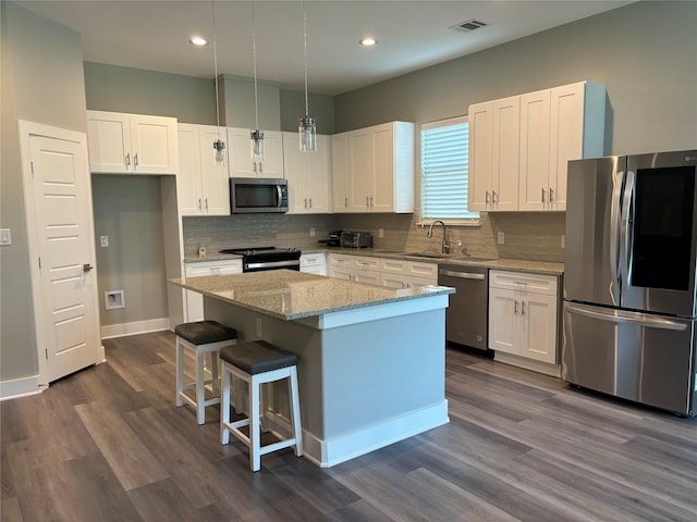 170 Nuuanu Ln, Bastrop, TX 78602 - kitchen featuring appliances with stainless steel finishes, a sink, a kitchen island, white cabinets, and dark wood-style floors