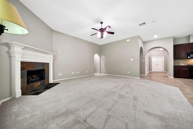 27506 Colin Springs Ln, Spring, TX 77386 - unfurnished living room featuring ceiling fan, arched walkways, light colored carpet, baseboards, and a tile fireplace