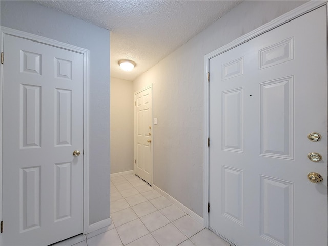 6722 Loch Bruceray Dr, Houston, TX 77084 - hallway featuring a textured ceiling, light tile patterned flooring, and baseboards
