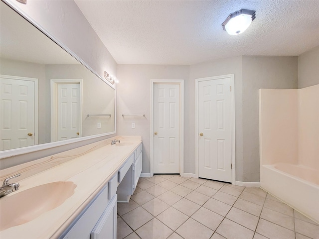 6722 Loch Bruceray Dr, Houston, TX 77084 - full bathroom featuring tile patterned flooring, a textured ceiling, double vanity, baseboards, and shower / washtub combination