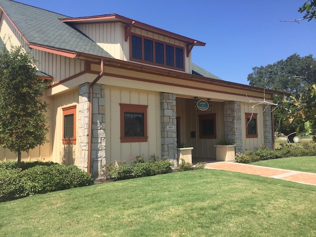 30307 Whistling Ln, Fulshear, TX 77441 - view of front of home with stone siding, a shingled roof, a front yard, and board and batten siding