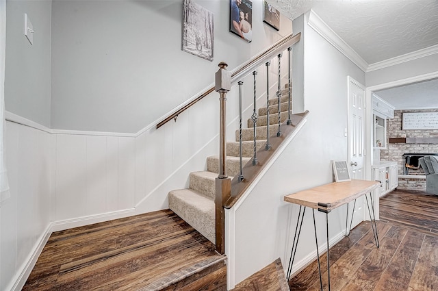 11607 Knobcrest Dr, Houston, TX 77070 - staircase featuring wood finished floors, ornamental molding, a stone fireplace, wainscoting, and a textured ceiling