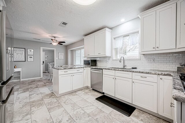11607 Knobcrest Dr, Houston, TX 77070 - kitchen with a sink, appliances with stainless steel finishes, a peninsula, a ceiling fan, and backsplash