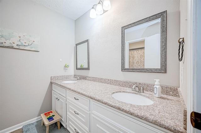 11607 Knobcrest Dr, Houston, TX 77070 - bathroom with double vanity, a textured ceiling, and baseboards