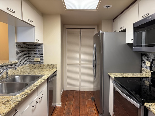 kitchen with stainless steel appliances, a sink, dark wood-style flooring, tasteful backsplash, and white cabinets