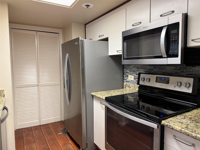 kitchen with appliances with stainless steel finishes, dark wood finished floors, backsplash, white cabinetry, and light stone counters
