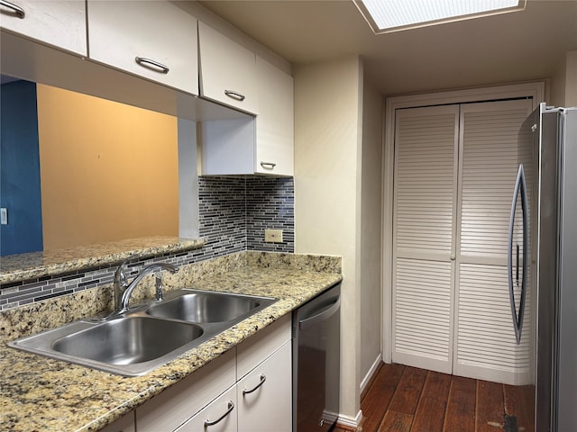 kitchen featuring stainless steel appliances, a sink, dark wood finished floors, decorative backsplash, and white cabinets