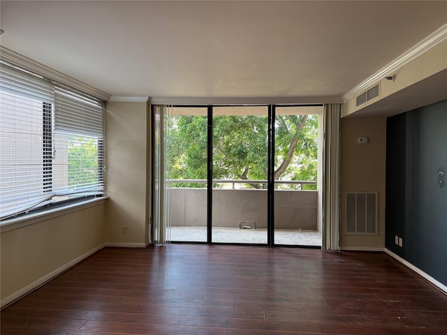 empty room featuring wood-type flooring, baseboards, crown molding, and floor to ceiling windows