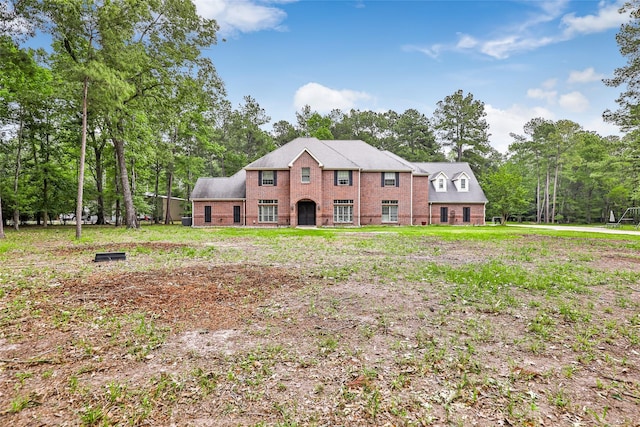 view of front of property featuring brick siding and view of wooded area