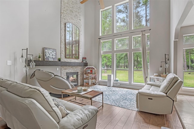 living area featuring a high ceiling, a fireplace, ceiling fan, arched walkways, and wood finished floors