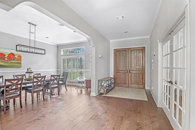 foyer featuring hardwood / wood-style floors, crown molding, and baseboards