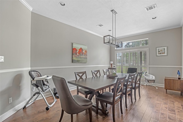 dining area featuring ornamental molding, hardwood / wood-style floors, a chandelier, a textured ceiling, and baseboards