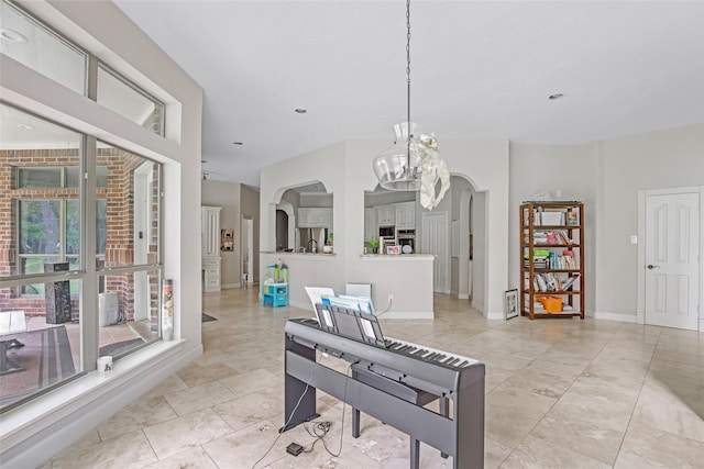 dining area with a chandelier, arched walkways, light tile patterned floors, and baseboards
