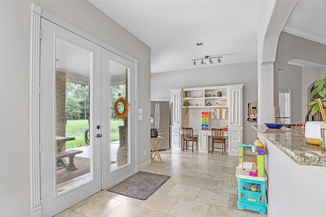 entrance foyer featuring french doors, arched walkways, light tile patterned floors, and track lighting