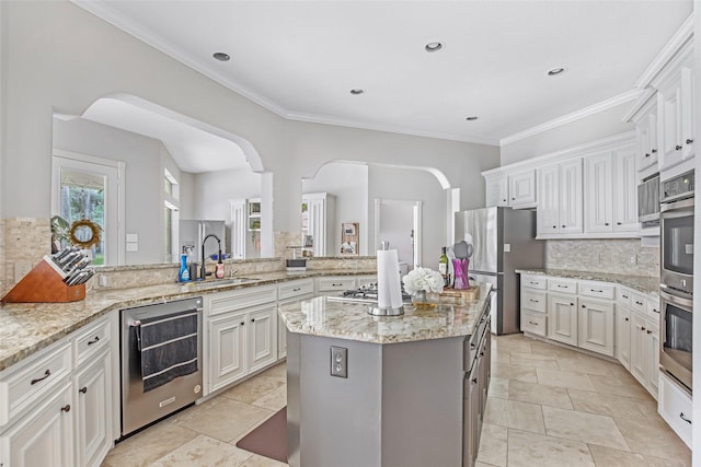 kitchen featuring appliances with stainless steel finishes, tasteful backsplash, a sink, a kitchen island, and ornamental molding
