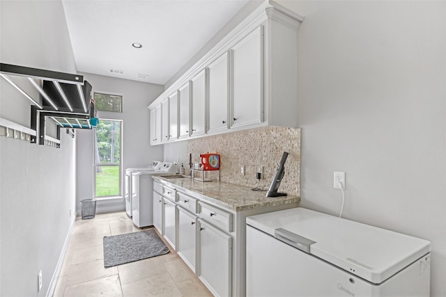 kitchen featuring washer and clothes dryer, decorative backsplash, white cabinets, refrigerator, and baseboards