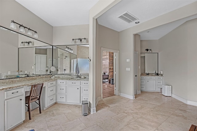 full bathroom featuring a shower stall, two vanities, and baseboards