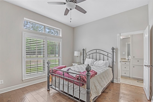 bedroom with light wood-type flooring, baseboards, ensuite bath, and a ceiling fan